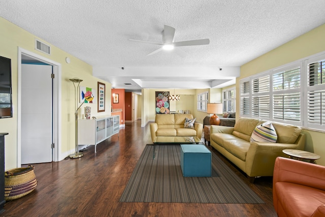 living room with ceiling fan with notable chandelier, dark hardwood / wood-style flooring, and a textured ceiling