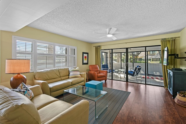 living room with a textured ceiling, ceiling fan, and dark hardwood / wood-style floors