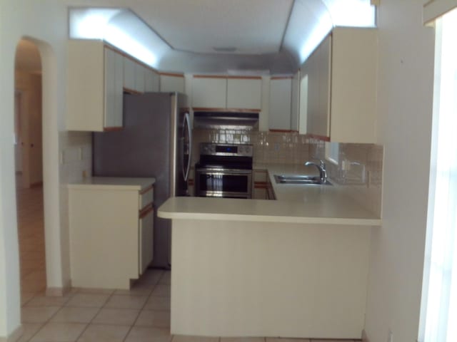 kitchen featuring stainless steel electric stove, tasteful backsplash, kitchen peninsula, sink, and light tile patterned flooring