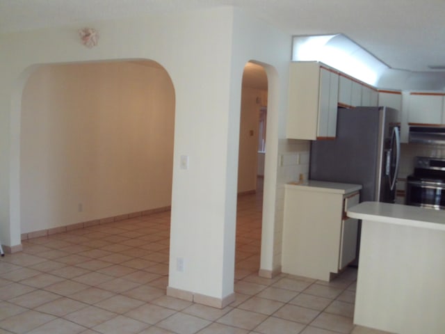 kitchen featuring light tile patterned flooring, range hood, and stainless steel range with electric cooktop