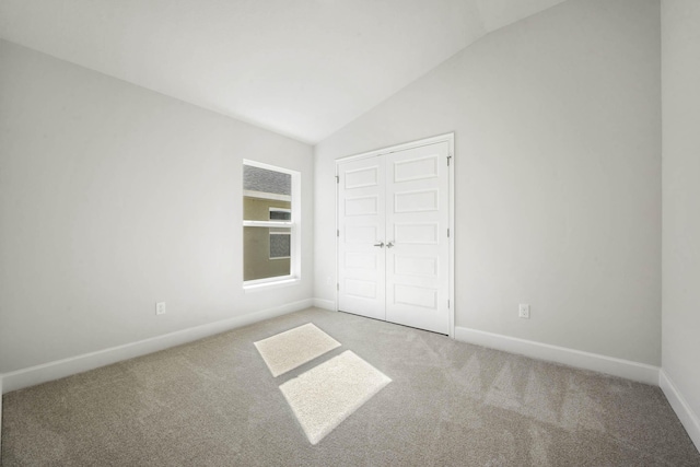 unfurnished bedroom featuring carpet flooring, a closet, and lofted ceiling