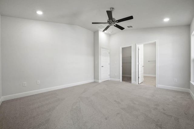 unfurnished bedroom with ceiling fan, ensuite bathroom, a walk in closet, light carpet, and a closet