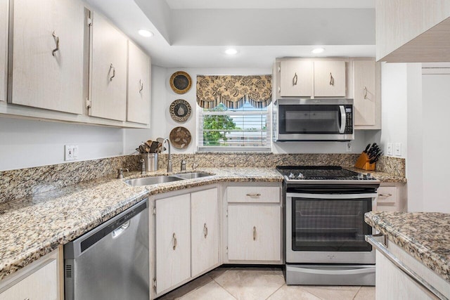 kitchen featuring light tile patterned floors, light stone counters, stainless steel appliances, and sink