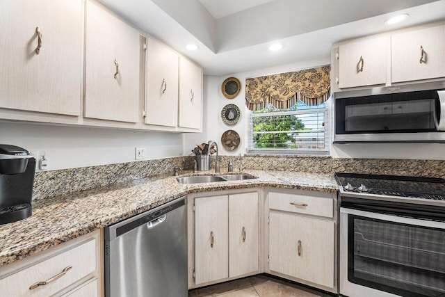 kitchen featuring stainless steel appliances, sink, light stone countertops, and light tile patterned flooring