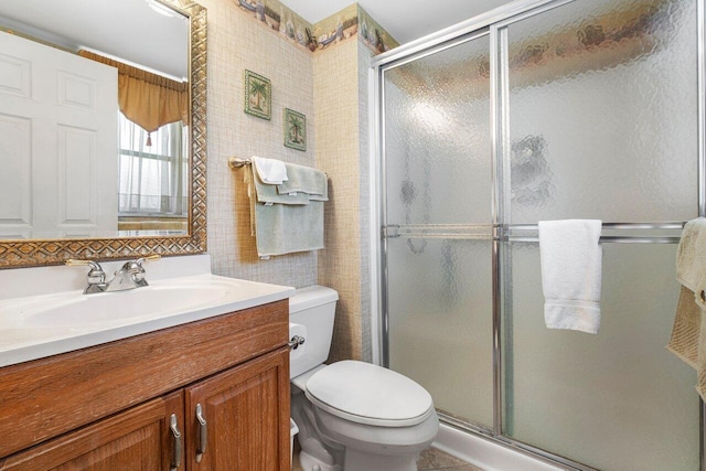 bathroom featuring vanity, toilet, and a shower with shower door