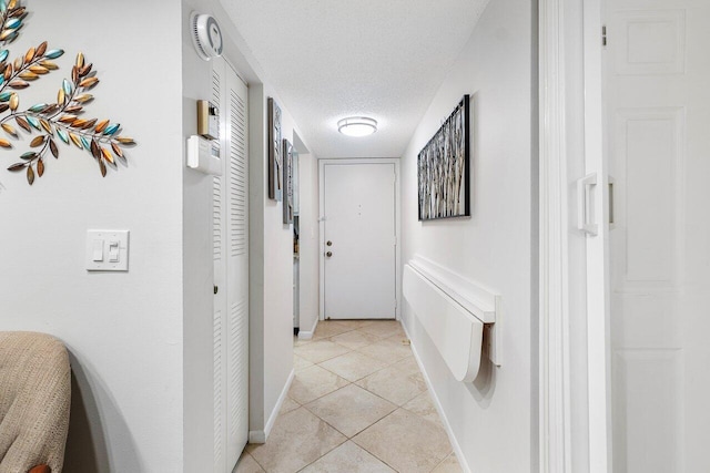 hallway featuring a textured ceiling and light tile patterned floors