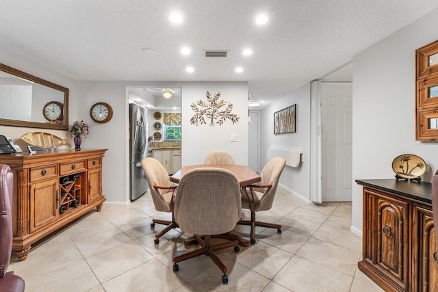 tiled dining area with ceiling fan and a textured ceiling