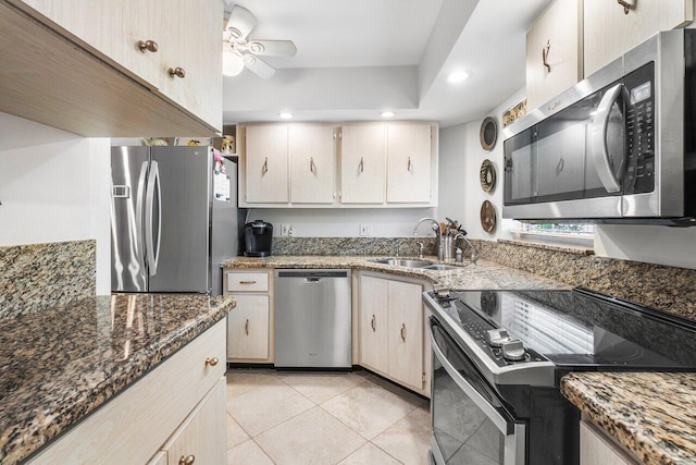 kitchen featuring dark stone countertops, light tile patterned floors, stainless steel appliances, sink, and ceiling fan