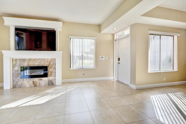 unfurnished living room with a textured ceiling, light tile patterned floors, and a fireplace