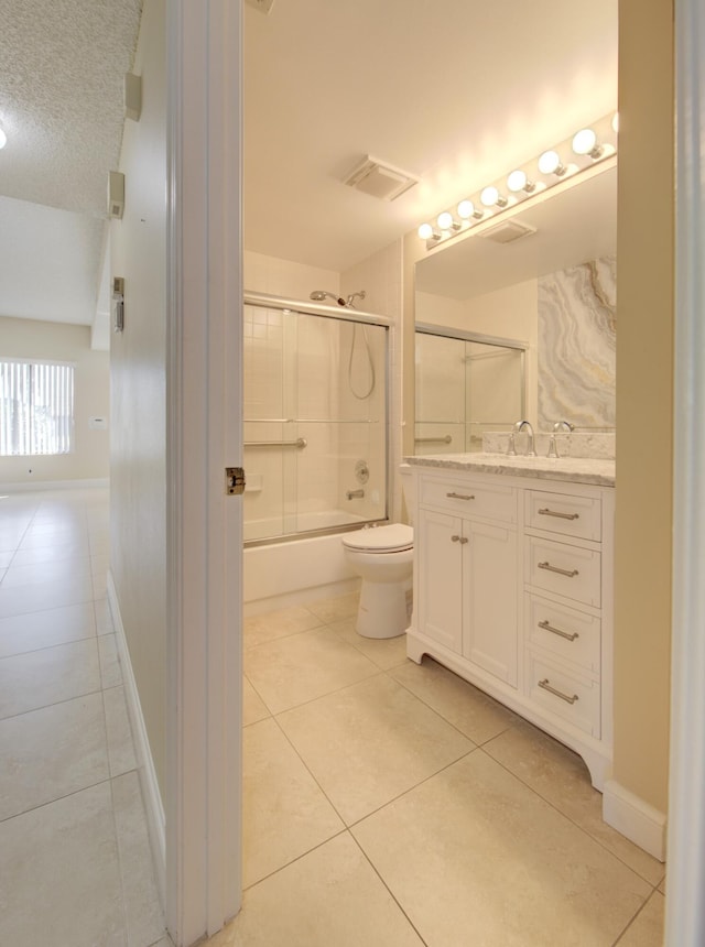 full bathroom featuring tile patterned flooring, a textured ceiling, toilet, shower / bath combination with glass door, and vanity