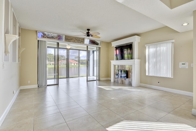 unfurnished living room featuring ceiling fan, light tile patterned flooring, a textured ceiling, and a high end fireplace