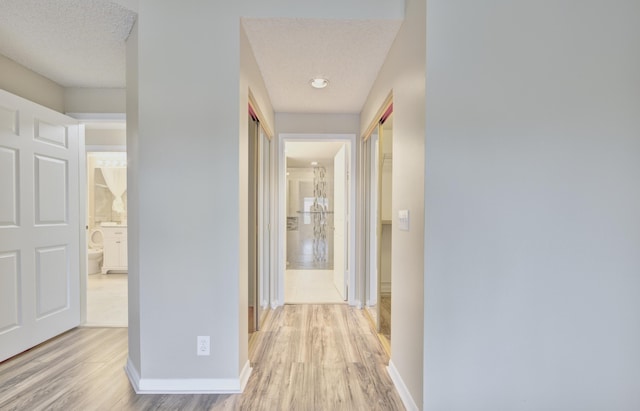 hall featuring a textured ceiling and light hardwood / wood-style flooring