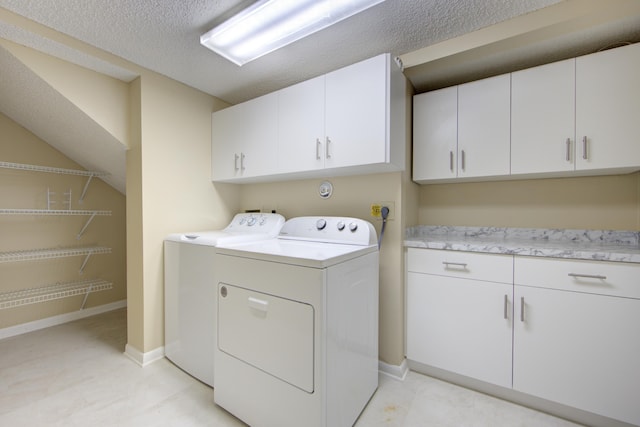 laundry area with washer and dryer, cabinets, and a textured ceiling