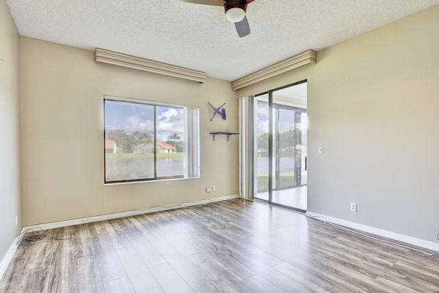 unfurnished room with light wood-type flooring and a textured ceiling