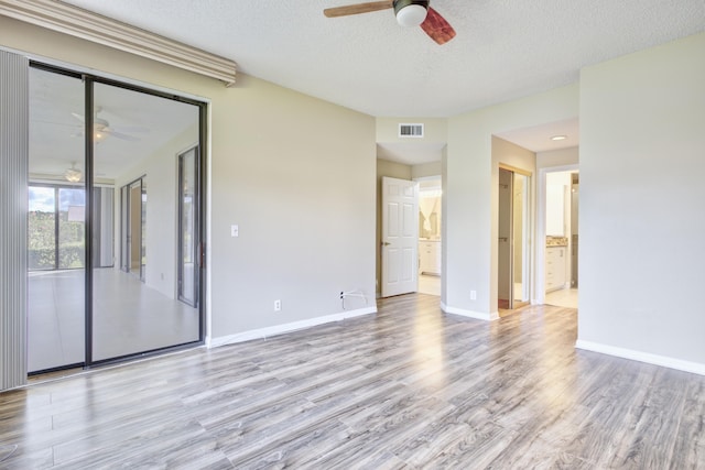 spare room featuring ceiling fan, light hardwood / wood-style floors, and a textured ceiling