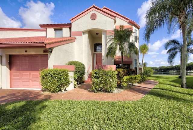 mediterranean / spanish home featuring a front lawn and a garage