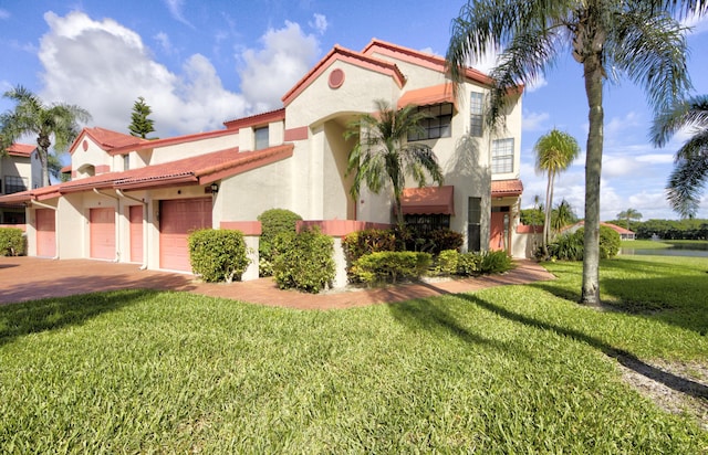 mediterranean / spanish-style home with a garage and a front lawn