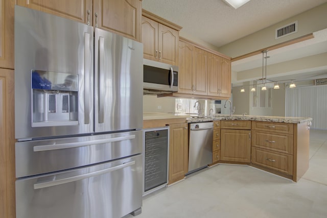 kitchen with appliances with stainless steel finishes, a textured ceiling, beverage cooler, sink, and pendant lighting