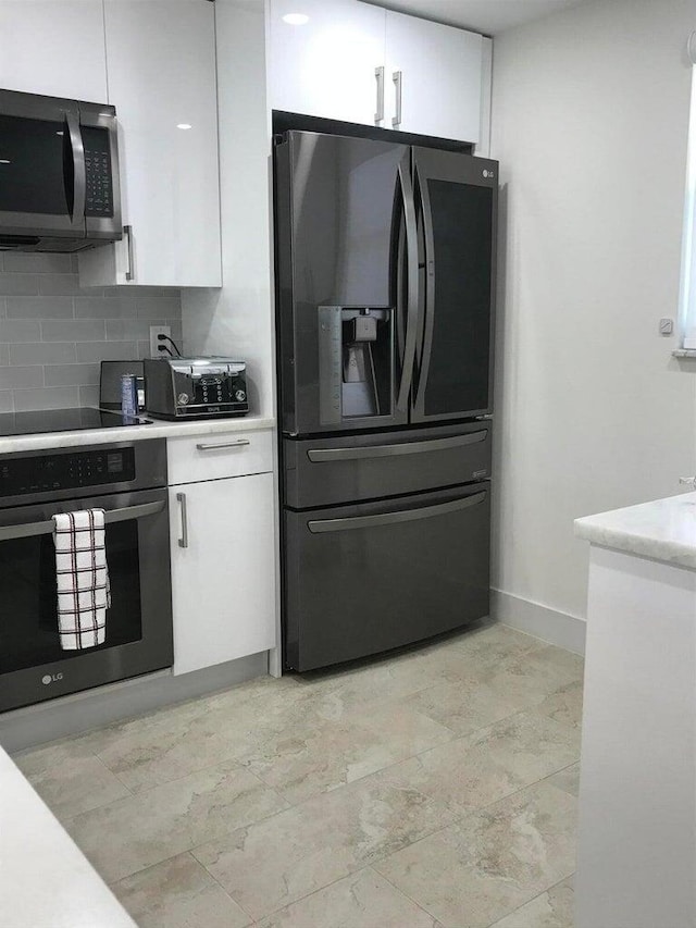 kitchen with black appliances, backsplash, light tile patterned flooring, and white cabinets