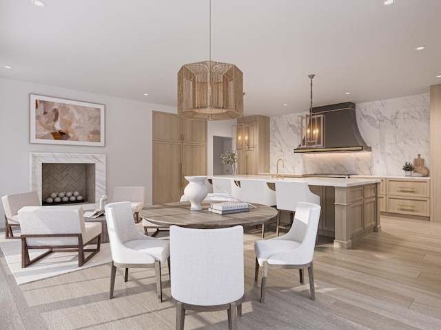 dining area featuring sink, light hardwood / wood-style floors, and a high end fireplace