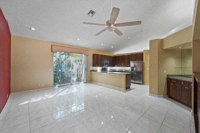 kitchen with a textured ceiling, vaulted ceiling, appliances with stainless steel finishes, light tile patterned floors, and ceiling fan