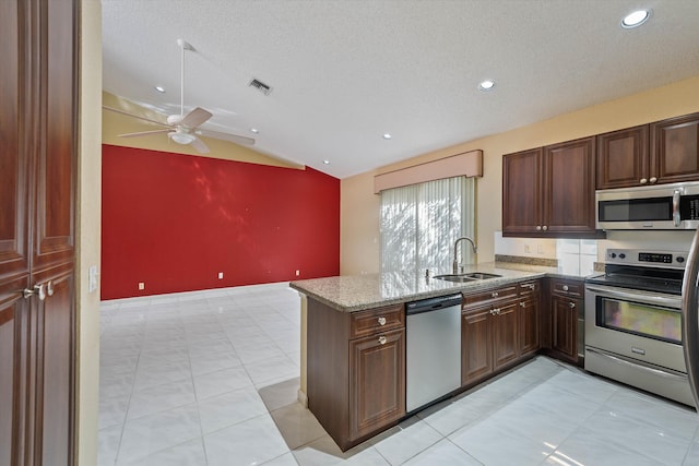 kitchen featuring ceiling fan, lofted ceiling, sink, a textured ceiling, and appliances with stainless steel finishes