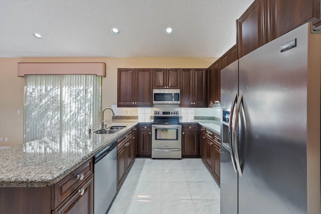 10860 Fairmont Village Dr, Lake Worth, FL 33449 - kitchen with light tile patterned floors, a sink, a peninsula, light stone countertops, and stainless steel appliances
