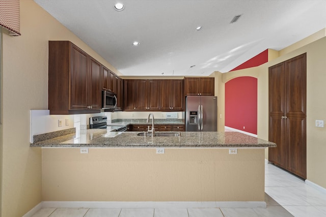 kitchen with sink, stainless steel appliances, kitchen peninsula, and dark stone counters