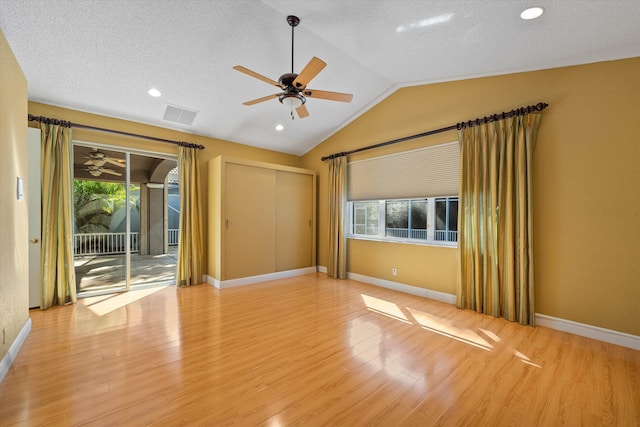 unfurnished room featuring light wood-type flooring, lofted ceiling, ceiling fan, and a textured ceiling