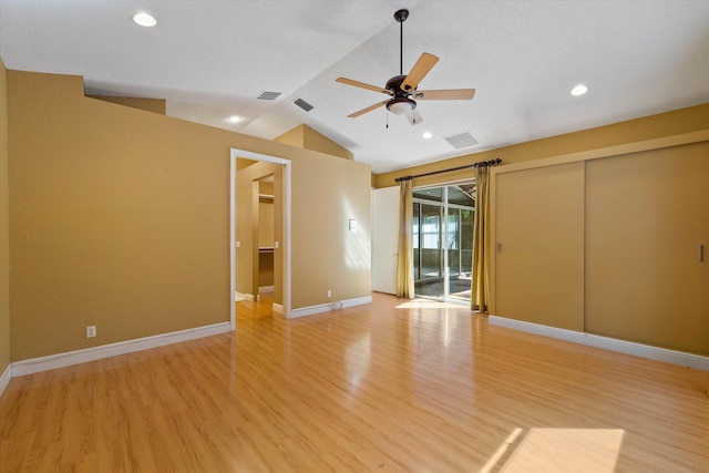 spare room featuring light hardwood / wood-style flooring, vaulted ceiling, ceiling fan, and a textured ceiling