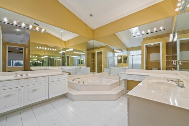 bathroom with tile patterned flooring, vaulted ceiling, tiled bath, and vanity