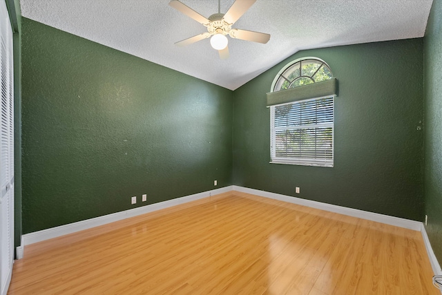 unfurnished room featuring lofted ceiling, ceiling fan, hardwood / wood-style floors, and a textured ceiling