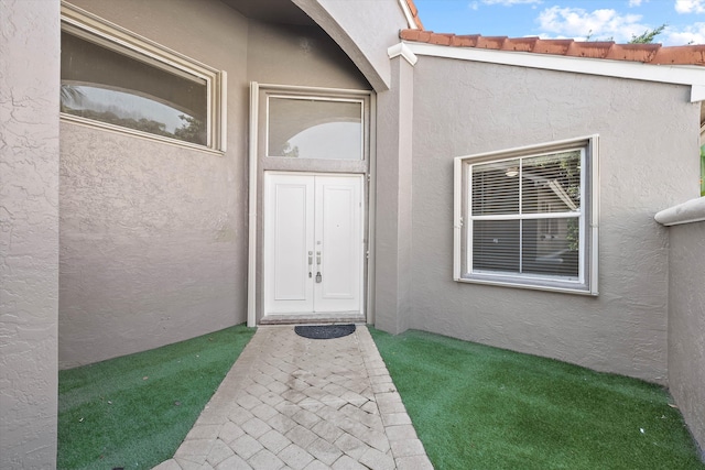 entrance to property featuring a lawn