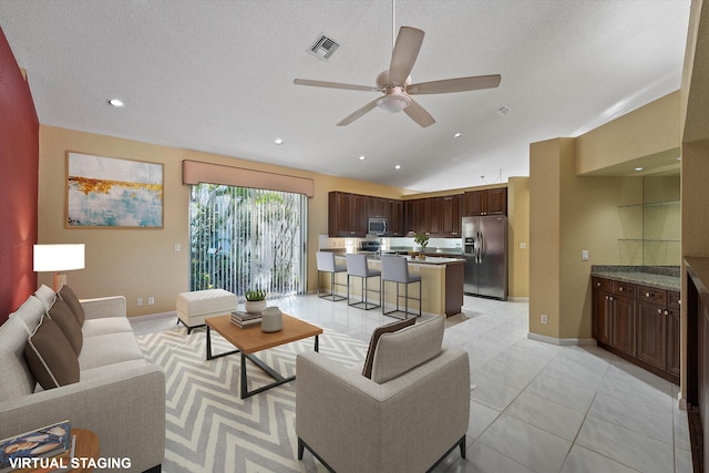 tiled living room featuring vaulted ceiling, ceiling fan, and a textured ceiling