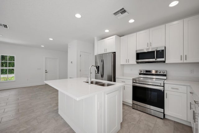 kitchen with a center island with sink, appliances with stainless steel finishes, white cabinetry, and light tile patterned flooring