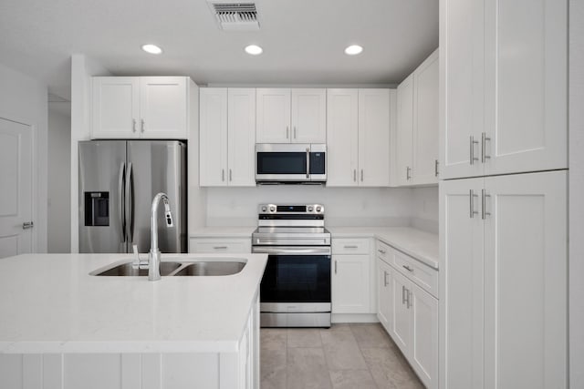 kitchen with white cabinets, light tile patterned flooring, stainless steel appliances, and sink