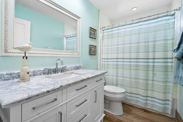 full bathroom with vanity, toilet, hardwood / wood-style flooring, and shower / bath combination with curtain