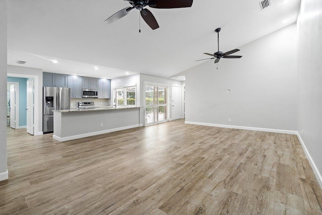 unfurnished living room with high vaulted ceiling, ceiling fan, sink, and light hardwood / wood-style flooring