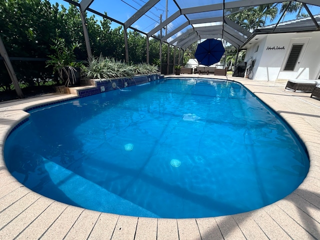 view of pool with glass enclosure, a patio area, and pool water feature