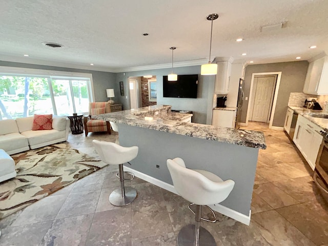 kitchen with decorative light fixtures, light stone countertops, and white cabinetry