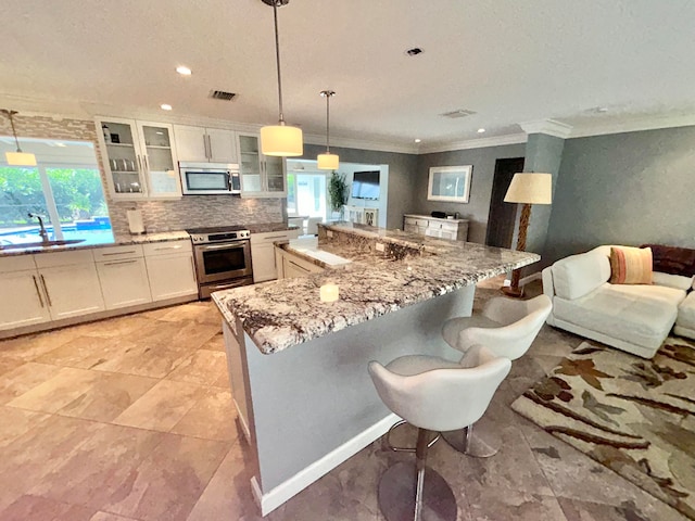 kitchen featuring appliances with stainless steel finishes, white cabinetry, sink, and pendant lighting