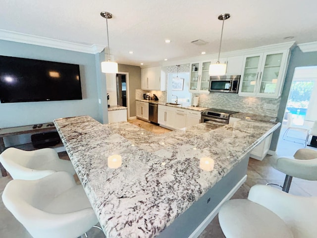 kitchen with a kitchen bar, hanging light fixtures, appliances with stainless steel finishes, and white cabinets