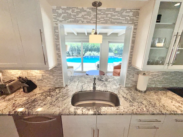 kitchen with white cabinets, decorative light fixtures, light stone counters, sink, and beam ceiling