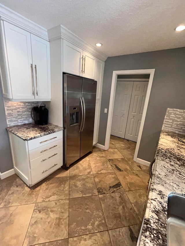 kitchen featuring a textured ceiling, stainless steel refrigerator with ice dispenser, stone countertops, decorative backsplash, and white cabinetry