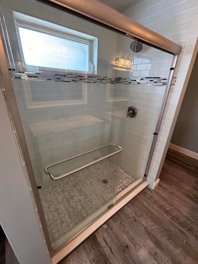 bathroom with plenty of natural light, hardwood / wood-style floors, and a shower with shower door