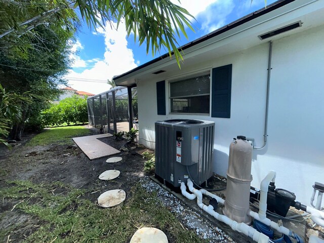 view of side of property featuring glass enclosure and central AC