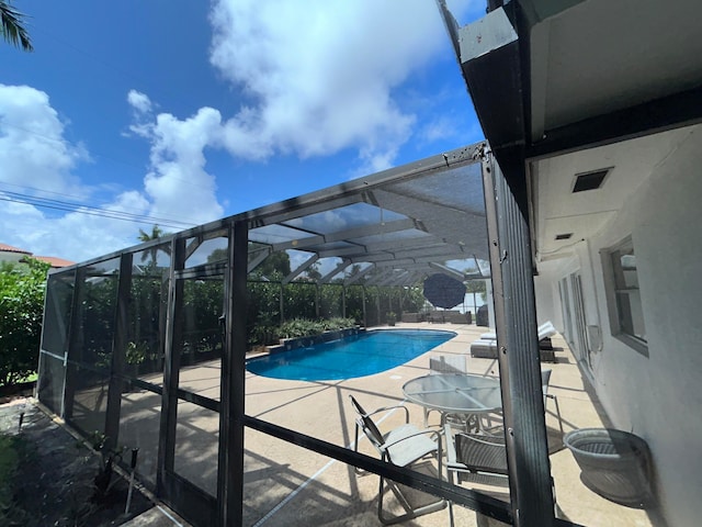 view of swimming pool with a patio area and glass enclosure