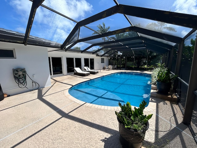 view of swimming pool with glass enclosure and a patio area