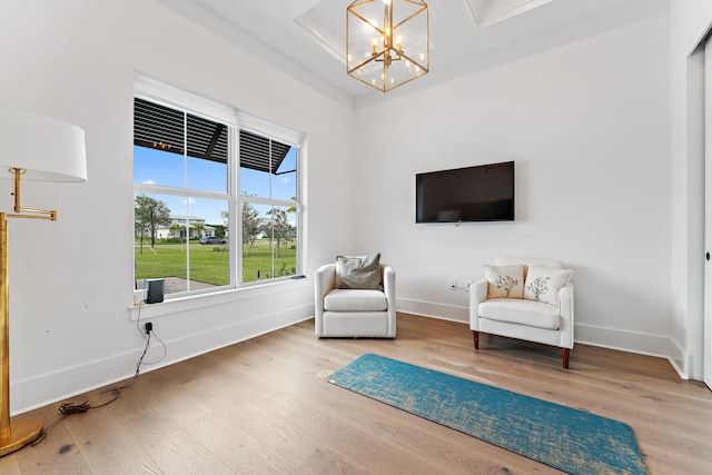 living area featuring baseboards, a chandelier, and wood finished floors