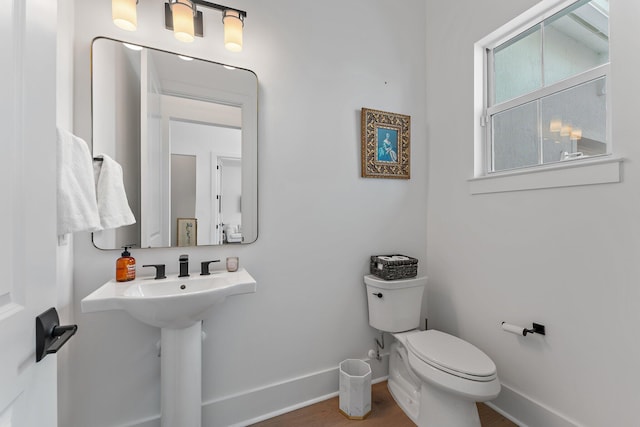 bathroom with toilet, baseboards, and wood finished floors